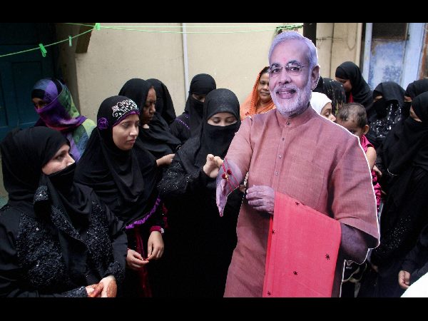 Muslim women tie rakhis on the wrists of a cut-out of Prime Minister Narendra Modi Muslim women tie rakhis on the wrists of a cut-out of Prime Minister Narendra Modi