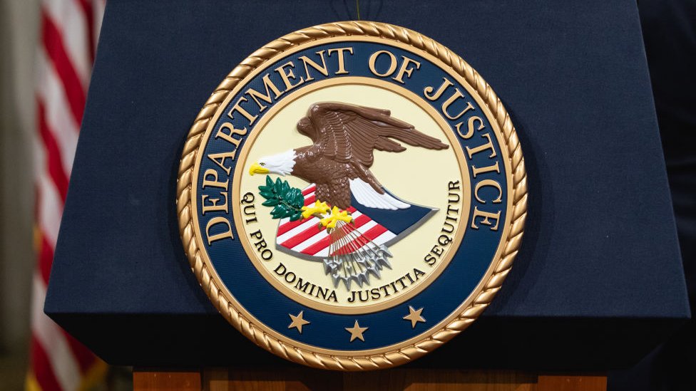 The Department of Justice seal is seen on a podium The Department of Justice seal is seen on a podium