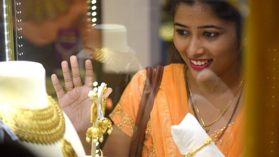బంగారు నగలను చూస్తున్న మహిళ బంగారు నగలను చూస్తున్న మహిళ